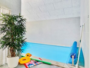 A swimming pool with a potted plant, inflatable toys, and a pool cleaning tool.