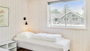 Una camera da letto con un letto, un comodino, una lampada a parete e una finestra con vista su una casa.