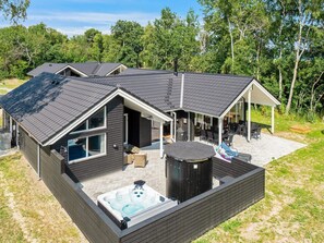 Uma casa moderna com hidromassagem, área de estar externa e um alpendre coberto.