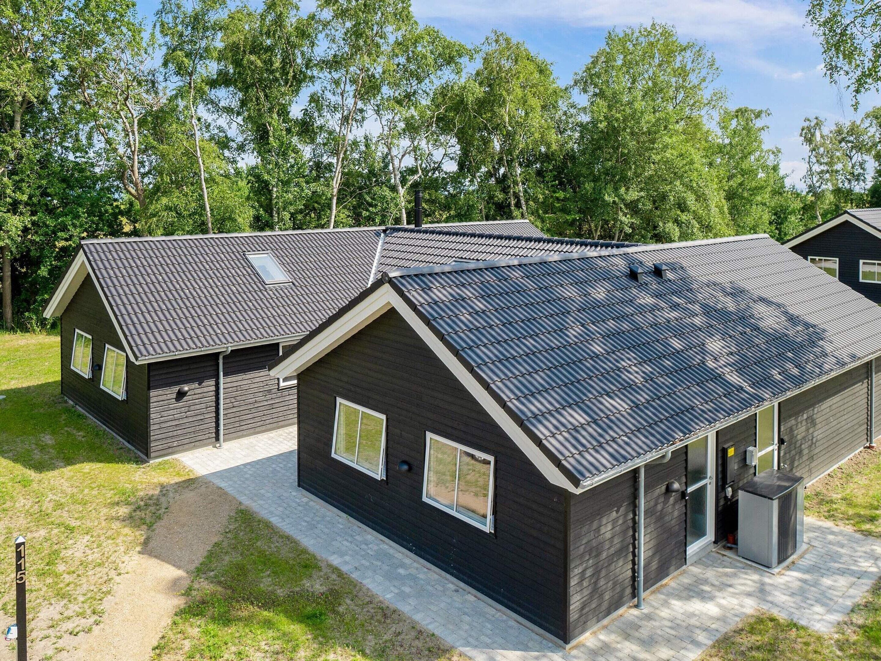 Un bâtiment moderne à l’extérieur sombre, doté de nombreuses fenêtres et d’un toit en pente.