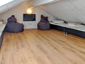 A loft-style room with wooden flooring, a flat-screen TV mounted on the wall, and two bean bag chairs. - 5 Star Holiday Home in Vaeggerlose (Vaeggerlose)