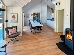 A modern interior with a dining area, a fireplace, and a view through a window. - 5 Star Holiday Home in Vaeggerlose (Vaeggerlose)