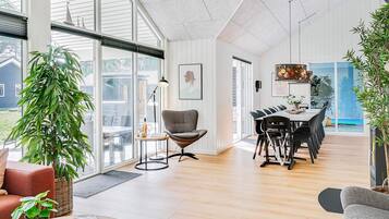 A spacious living area with a dining table, a sofa, and a large window.