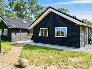 A two-story building with a dark exterior, a covered porch, and a visible garage door. - 5 Star Holiday Home in Vaeggerlose (Vaeggerlose)