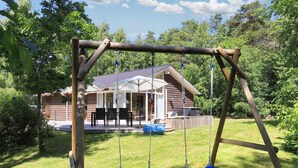 A wooden swing set in a backyard with a house in the background.