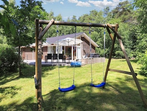 Un portique en bois installé dans un jardin, avec une maison en arrière-plan.