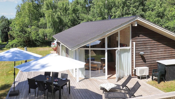 A wooden deck with outdoor furniture, a covered patio area, and a glass-enclosed room.