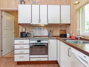 A compact kitchen with white cabinets, a built-in oven, a coffee maker, and a sink. - 4 Star Holiday Home in Laeso (Læsø)