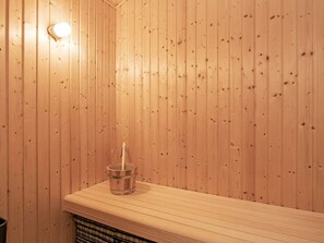 Una sauna con paredes de madera, un banco y un balde.
