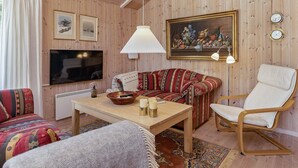 A cozy living room with a sofa, a chair, a table, a TV, and a painting.