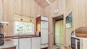 A kitchen with wooden walls, a window, a refrigerator, a sink, and a microwave.