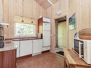 Une cuisine avec des murs en bois, une fenêtre, un réfrigérateur, un évier et un four à micro-ondes.