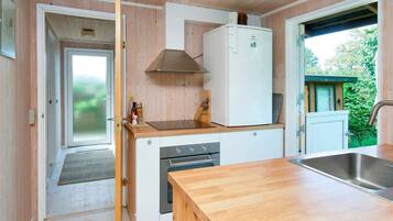 Una cocina compacta con armarios de madera, horno empotrado y pileta de acero inoxidable.
