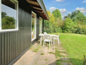 A house with a dark exterior, a patio with a table and chairs, and a grassy yard.