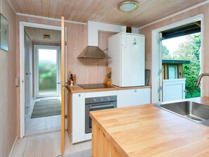 A compact kitchen with wooden cabinetry, a built-in oven, and a stainless steel sink. - 6 Person Holiday Home in Farevejle (Faarevejle)