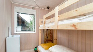A bunk bed room with a window, a small white cabinet, and a green object on the floor.