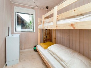 A bunk bed room with a window, a small white cabinet, and a green object on the floor. - 6 Person Holiday Home in Farevejle (Faarevejle)
