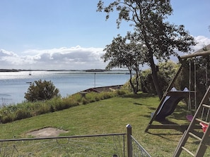A grassy area with a playground and a view of a body of water with boats. - 4 Person Holiday Home in Martofte (Martofte)