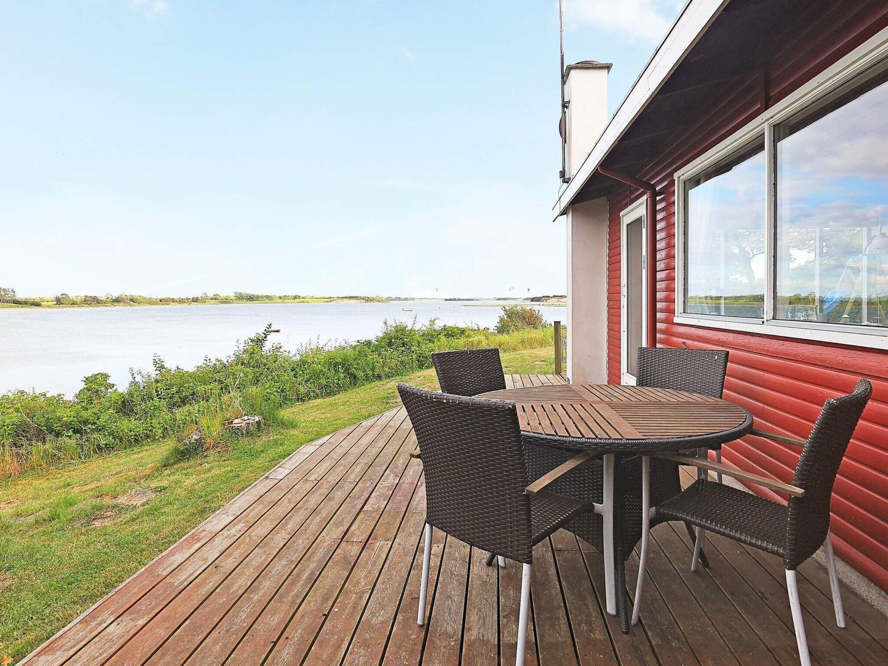 A wooden deck with a table and chairs overlooking a body of water.