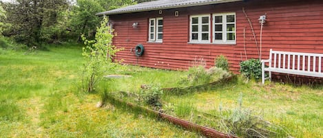 Una casa de madera roja con cerca blanca, rodeada de césped y árboles.