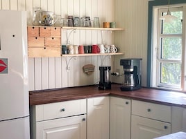 Una cocina con armarios de madera, cafetera y ventana con vistas a la vegetación.