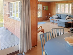 A wooden cabin interior with a blue sofa, a dining table, and a curtain. - 6 Person Holiday Home in Hurup Thy (Hurup Thy)