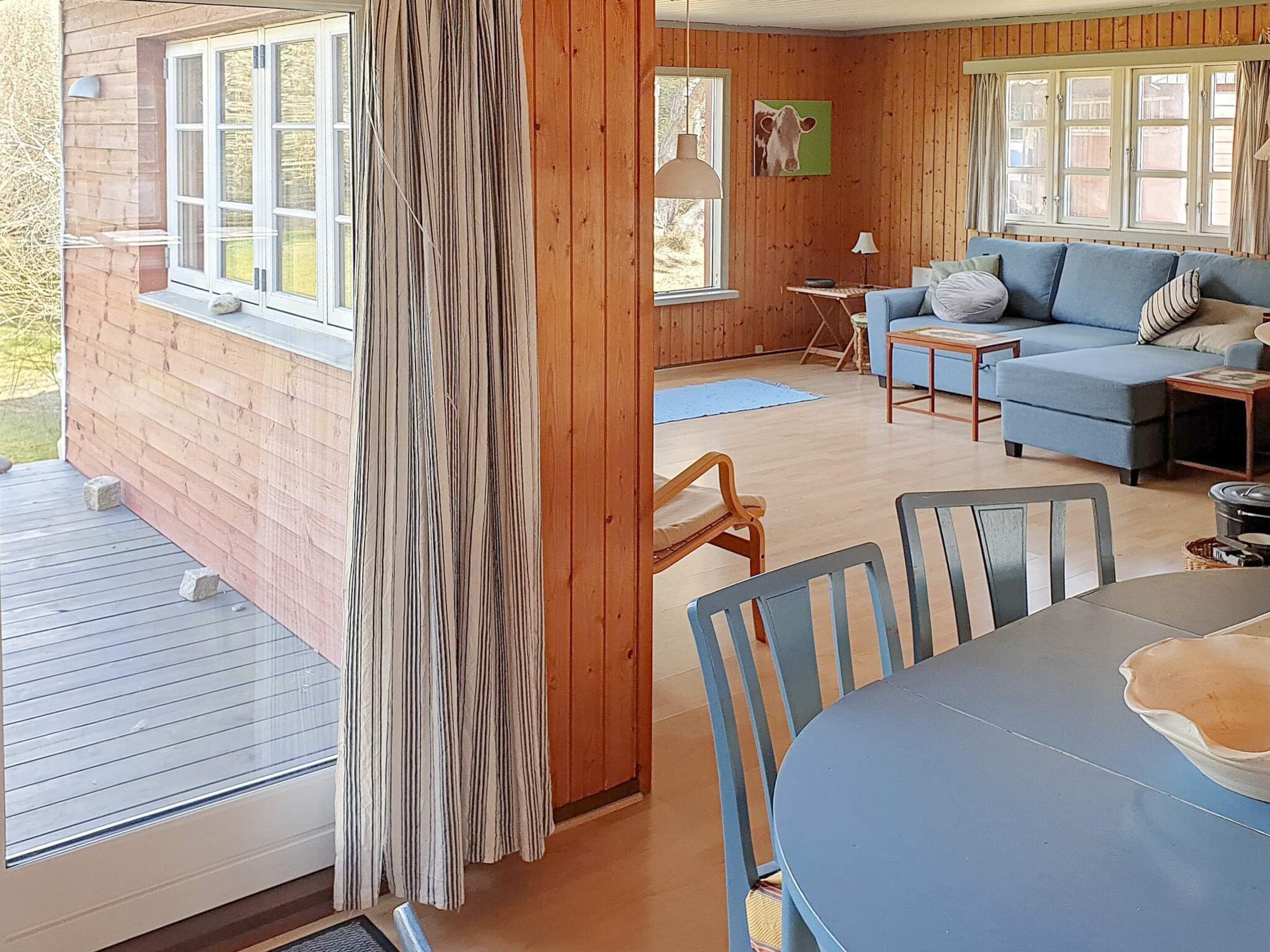 L’intérieur d’un chalet en bois comprend un coin repas, un canapé et une fenêtre donnant sur un paysage naturel.