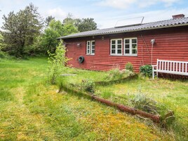 Una casa de madera roja con cerca blanca, rodeada de césped y árboles.