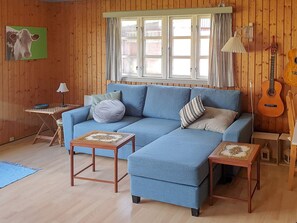 A room with a blue sofa, two small tables, a guitar, and a window with curtains. - 6 Person Holiday Home in Hurup Thy (Hurup Thy)