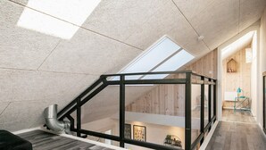 Un loft moderno con finestra a lucernario, pavimento in legno e un soppalco.