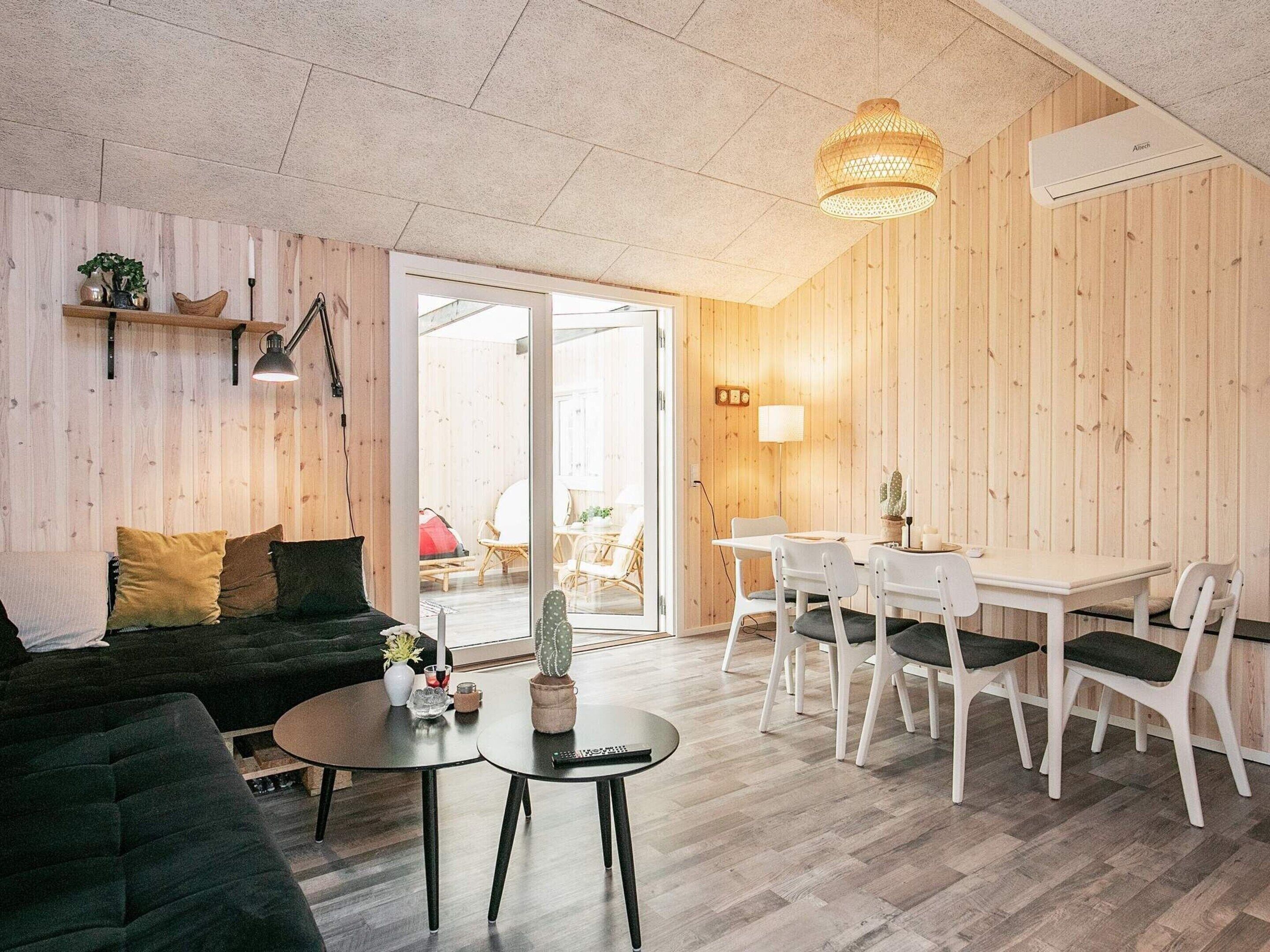 A modern living room with a sofa, a round coffee table, and a dining area with a table and chairs.