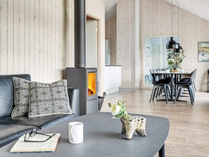 A modern living room with a sofa, a coffee table with a mug and glasses, a decorative plant, and a fireplace.