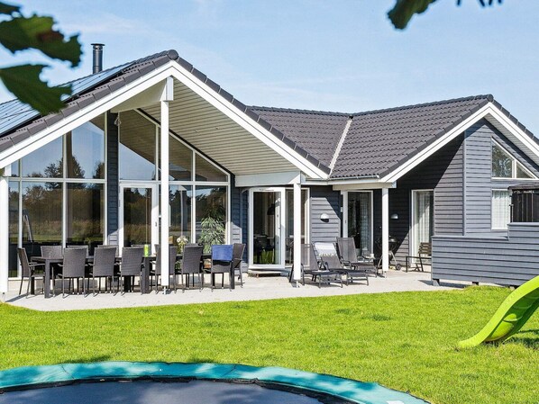A modern house with a covered patio, large windows, and a swimming pool.