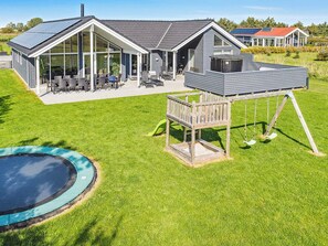 Ett hus med en stor veranda, en swimmingpool och en separat trähusliknande byggnad med en gunga.