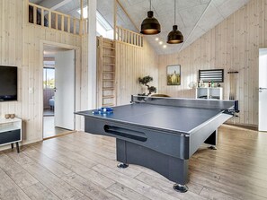 A ping pong table in a room with wooden walls and a loft area.