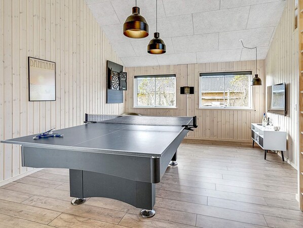 A ping pong table in a room with wooden walls, a TV, and a window.