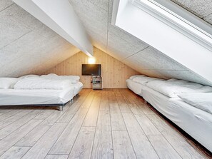 A room with two beds, a television, and a wooden floor.