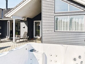 A spa area with a hot tub, outdoor seating, and a covered patio.