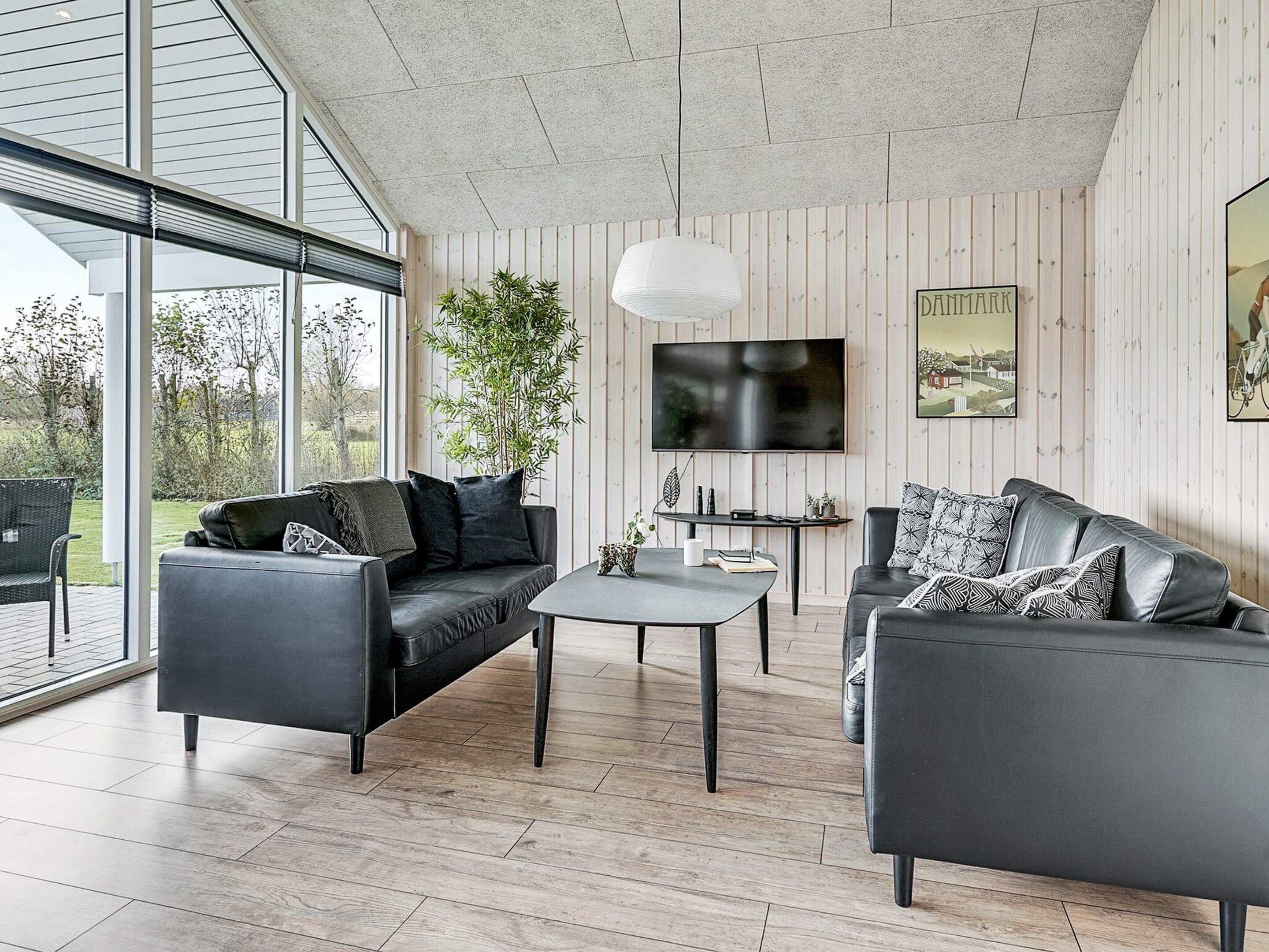 A modern living room with a large window, a flat-screen TV, and a dining area.