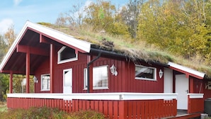 A red wooden cabin with a sloped roof, white trim, and a small porch. - 6 Person Holiday Home in Vatne (Ålesund)