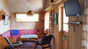A cozy cabin interior with a wooden interior, a sofa, two chairs, a television, and a window with curtains. - 6 Person Holiday Home in Vatne (Ålesund)