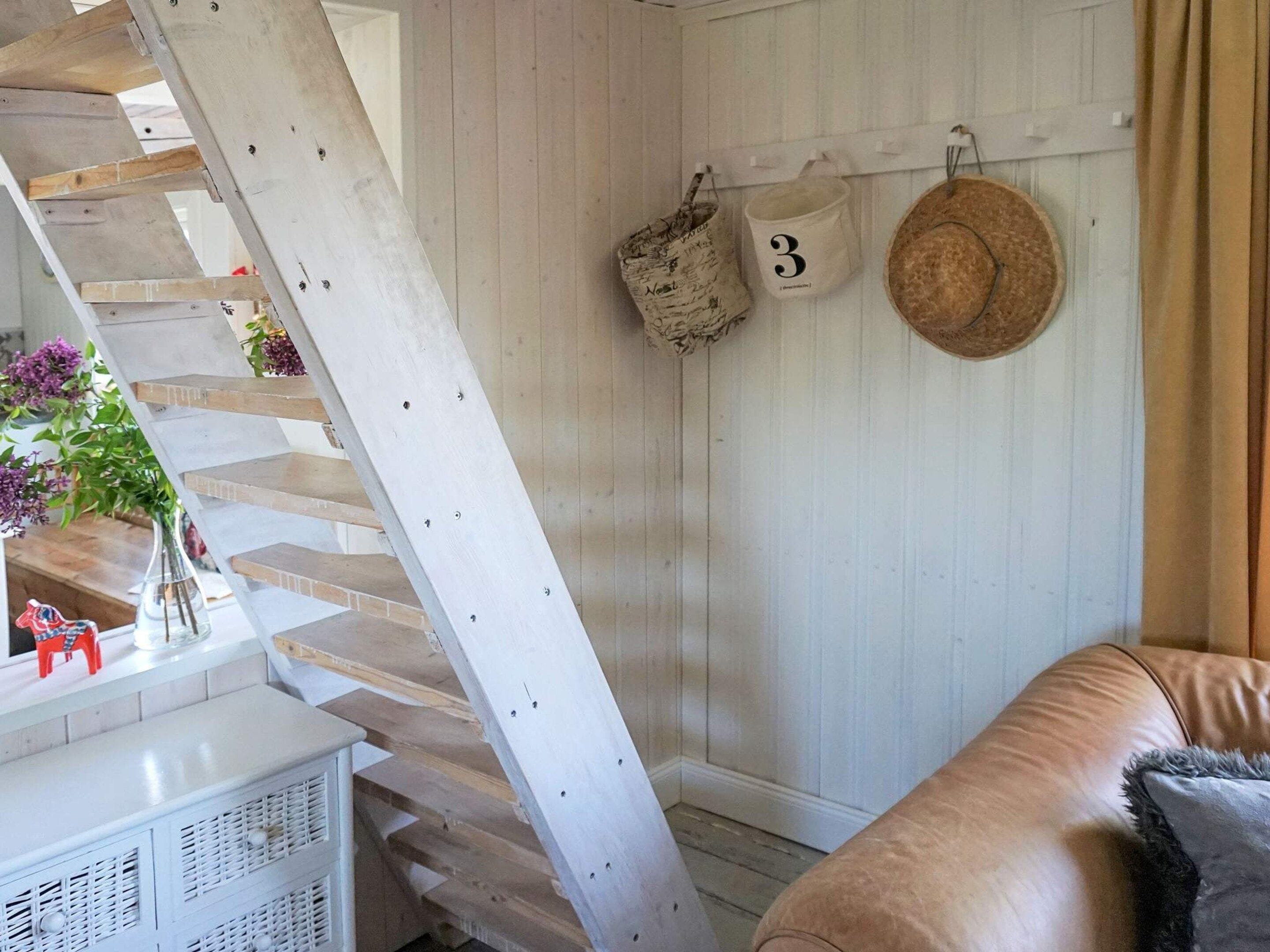 Una escalera con barandilla blanca, una pared blanca con un letrero con el número 3, y un sofá de cuero marrón.