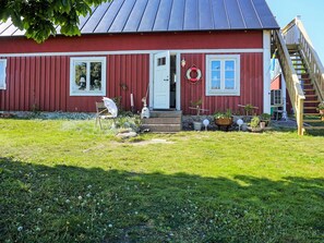 A red wooden house with a metal roof, a front door, and a small porch area with potted plants. - 6 Person Holiday Home in Solvesborg (Sölvesborg)