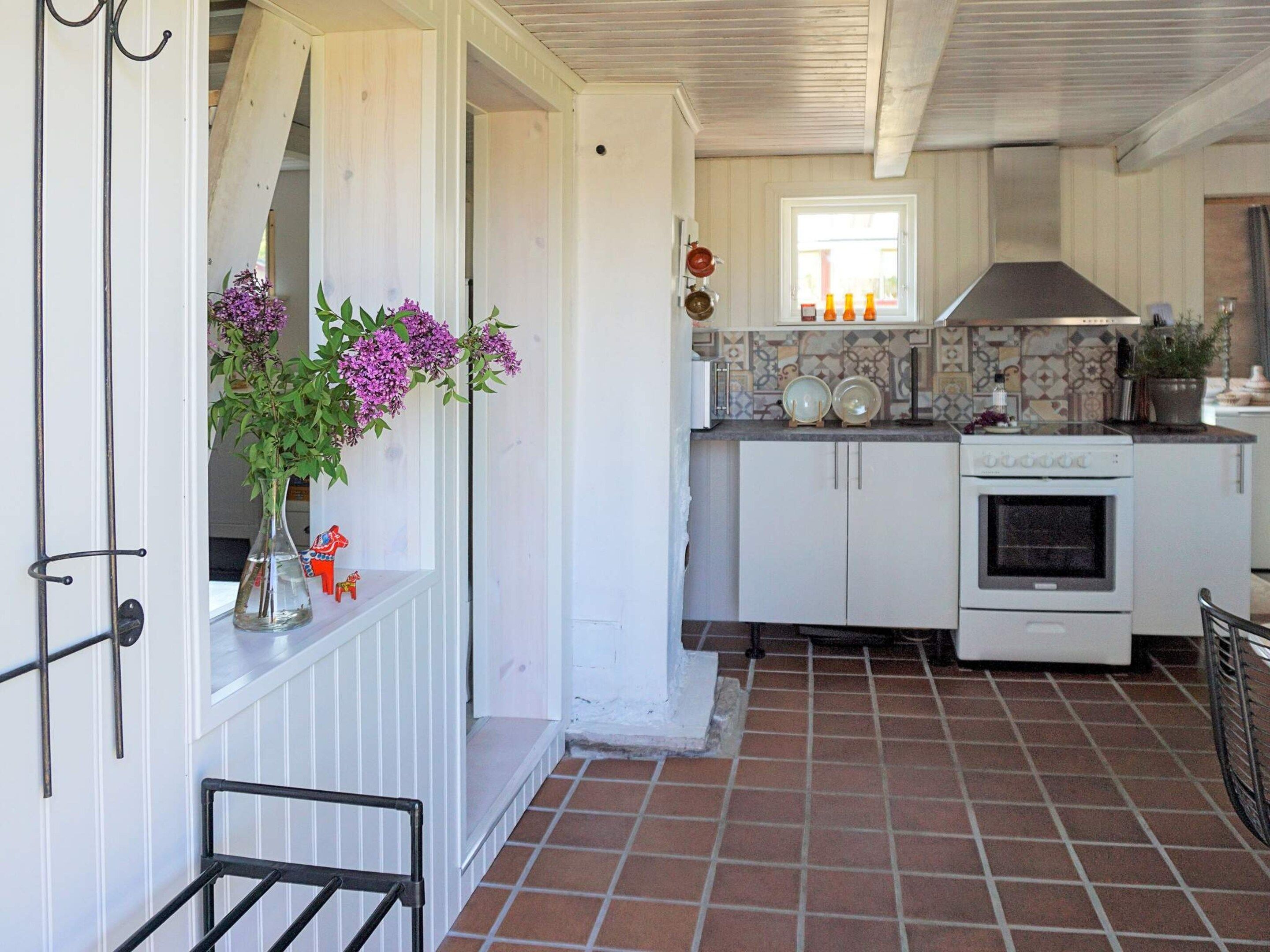 A kitchen with white cabinets, a tiled floor, and a window with a view.