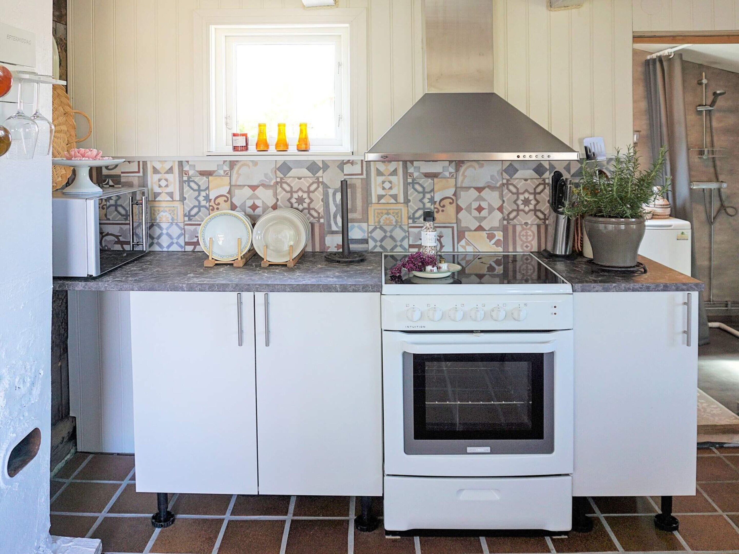 Una cocina con armarios blancos, estufa y salpicadero de azulejos.