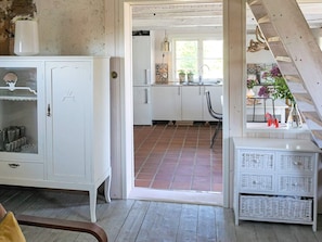 A room with a white cabinet, a wicker table with baskets, and a view into a kitchen with a tiled floor. - 6 Person Holiday Home in Solvesborg (Sölvesborg)