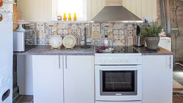 A kitchen with white cabinets, a stove, and a window above the counter.