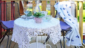 A round table with a white lace tablecloth, two chairs with blue cushions, a small potted plant, and a white cloth draped over one chair. - 6 Person Holiday Home in Solvesborg (Sölvesborg)