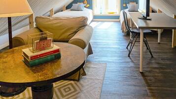 A cozy attic bedroom with a bed, a desk, and a table with books.