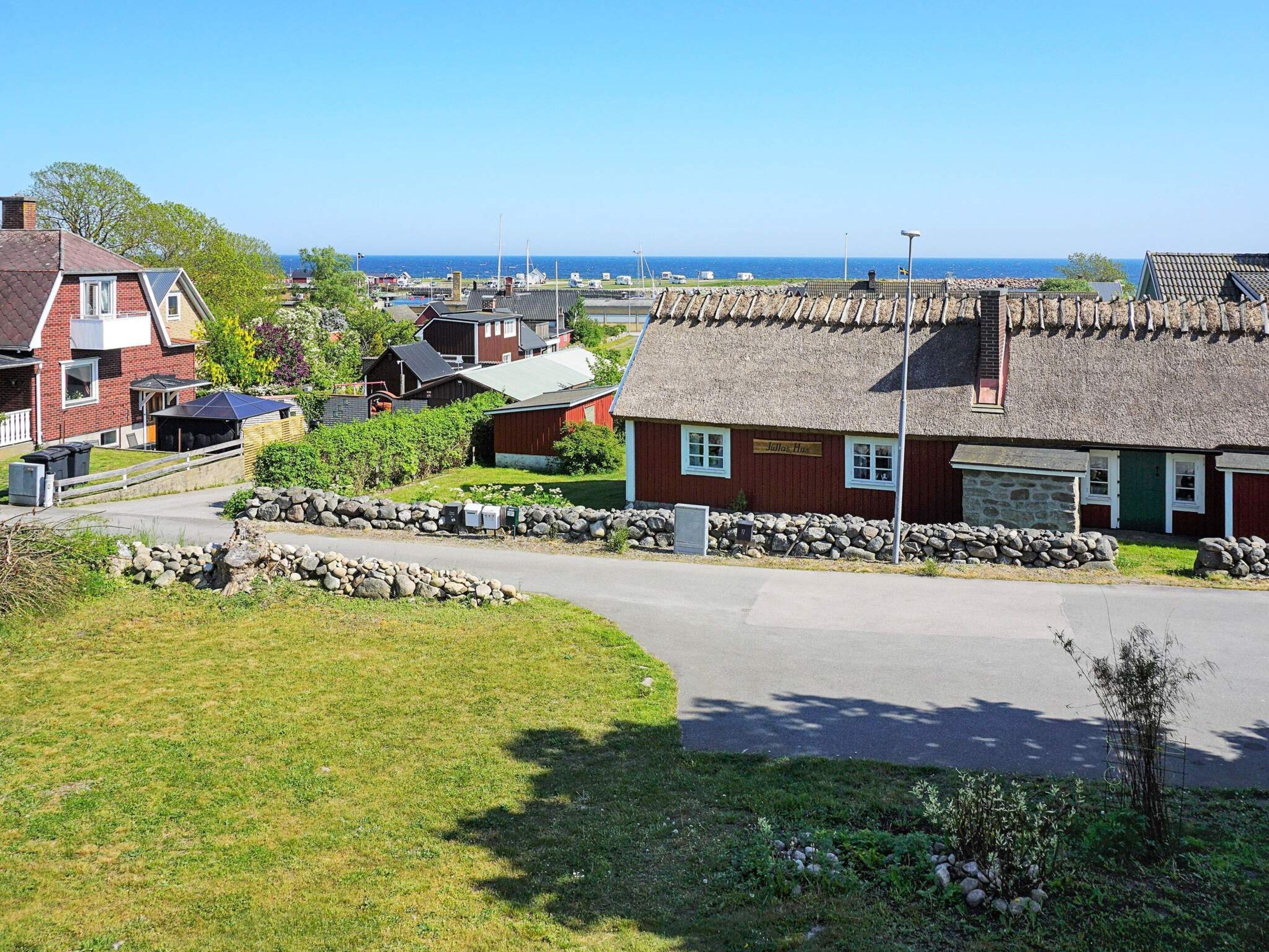 A coastal village with traditional houses, a stone wall, and a clear view of the sea.